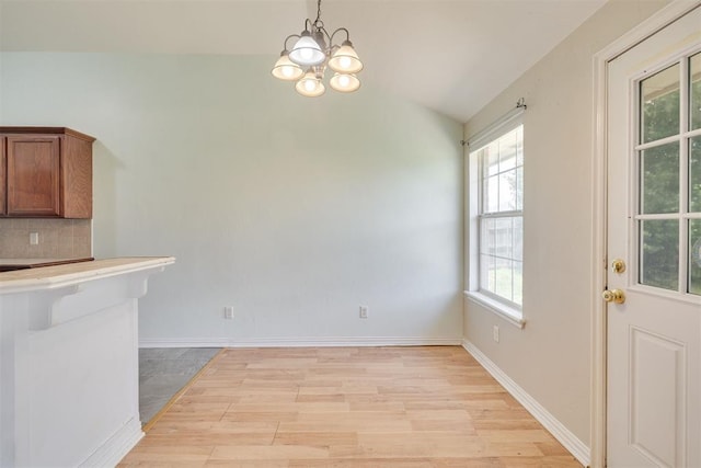 5600 Darla Dr, Oklahoma City, OK 73135 - kitchen featuring brown cabinetry, a chandelier, plenty of natural light, tasteful backsplash, and vaulted ceiling