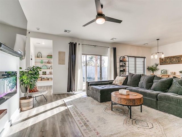 8324 NW 151st Ter, Edmond, OK 73013 - living room featuring wood finished floors, ceiling fan, a chandelier, and baseboards