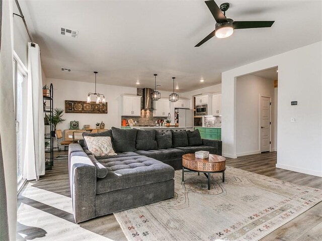 8324 NW 151st Ter, Edmond, OK 73013 - living area with light wood-style floors, ceiling fan, a chandelier, and baseboards