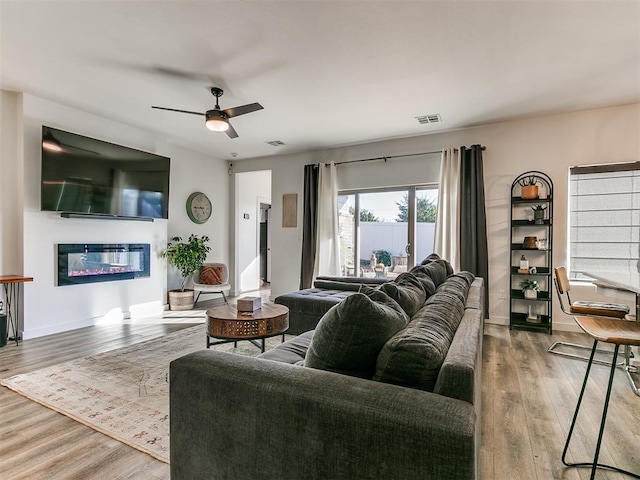 8324 NW 151st Ter, Edmond, OK 73013 - living room with a glass covered fireplace, wood finished floors, and ceiling fan