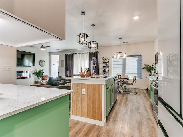 8324 NW 151st Ter, Edmond, OK 73013 - kitchen with green cabinets, light wood-style flooring, an island with sink, and ceiling fan