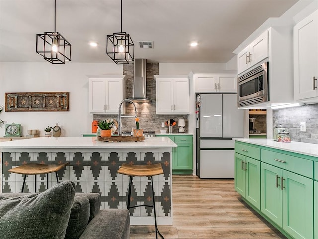 8324 NW 151st Ter, Edmond, OK 73013 - kitchen with wall chimney range hood, freestanding refrigerator, stainless steel microwave, decorative backsplash, and white cabinetry