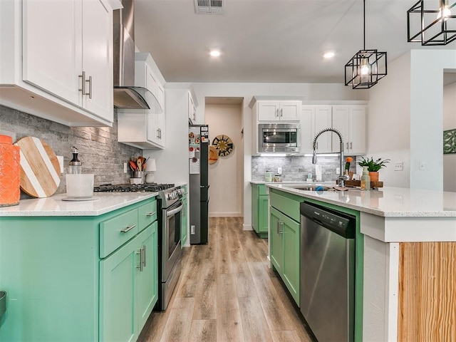 8324 NW 151st Ter, Edmond, OK 73013 - kitchen featuring appliances with stainless steel finishes, wall chimney range hood, green cabinets, a sink, and tasteful backsplash