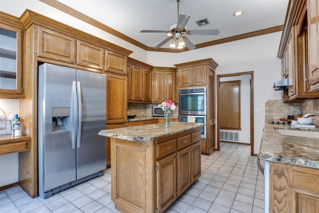 12432 Hastings Rd, Midwest City, OK 73130 - kitchen featuring appliances with stainless steel finishes, backsplash, a ceiling fan, brown cabinetry, and light stone countertops