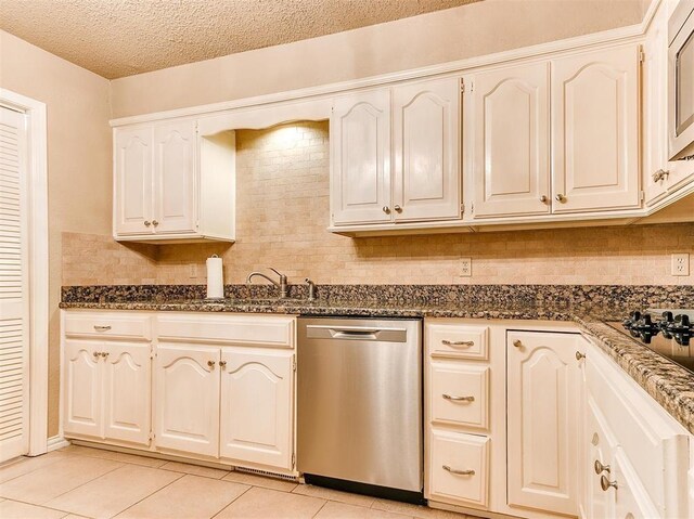 7817 Old Hickory Ln, Oklahoma City, OK 73116 - kitchen featuring stainless steel dishwasher, light tile patterned flooring, decorative backsplash, dark stone countertops, and a textured ceiling