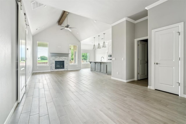 1513 Reid Pryor Rd, Norman, OK 73072 - unfurnished living room featuring beam ceiling, a ceiling fan, light wood-style floors, a fireplace, and high vaulted ceiling