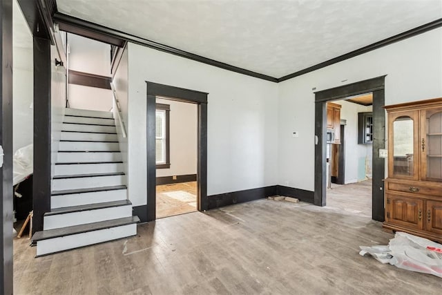 1901 E University Ave, Guthrie, OK 73044 - unfurnished living room featuring light wood-type flooring, stairs, and crown molding