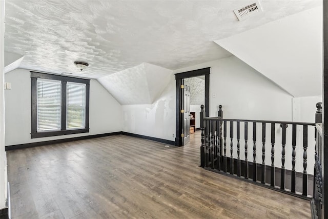 1901 E University Ave, Guthrie, OK 73044 - bonus room featuring wood finished floors, vaulted ceiling, and a textured ceiling