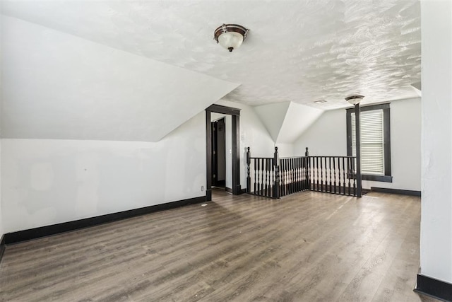 1901 E University Ave, Guthrie, OK 73044 - additional living space featuring wood finished floors, lofted ceiling, and a textured ceiling