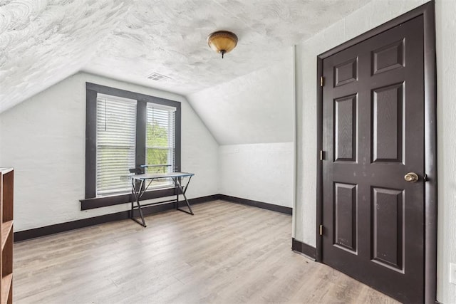 1901 E University Ave, Guthrie, OK 73044 - additional living space with wood finished floors, vaulted ceiling, and a textured ceiling