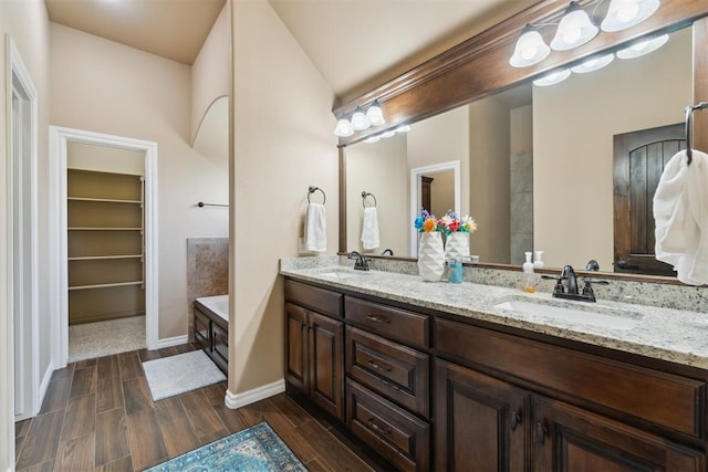 bathroom with double vanity, wood tiled floors, baseboards, and a spacious closet
