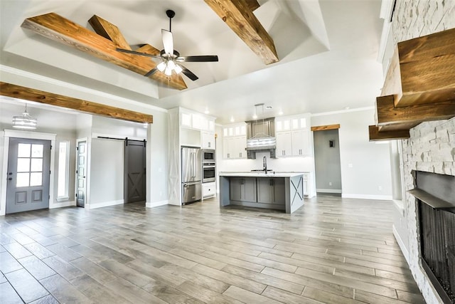 12016 SW 50th St, Mustang, OK 73064 - unfurnished living room featuring a barn door, a ceiling fan, a fireplace, wood finished floors, and recessed lighting