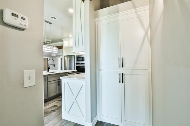 12016 SW 50th St, Mustang, OK 73064 - interior space with appliances with stainless steel finishes, pendant lighting, light wood-type flooring, and white cabinets