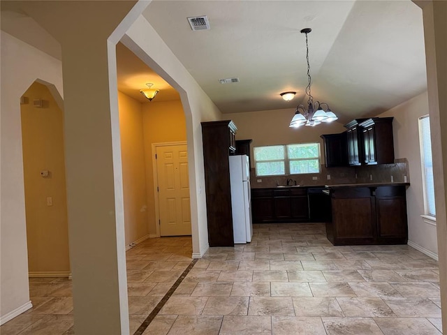1523 Morland St, Norman, OK 73071 - kitchen with freestanding refrigerator, a sink, arched walkways, a chandelier, and stone tile floors