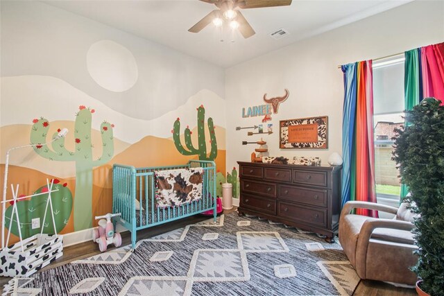 3154 Red Ridge Dr, Blanchard, OK 73010 - bedroom with wood finished floors, baseboards, a crib, and ceiling fan