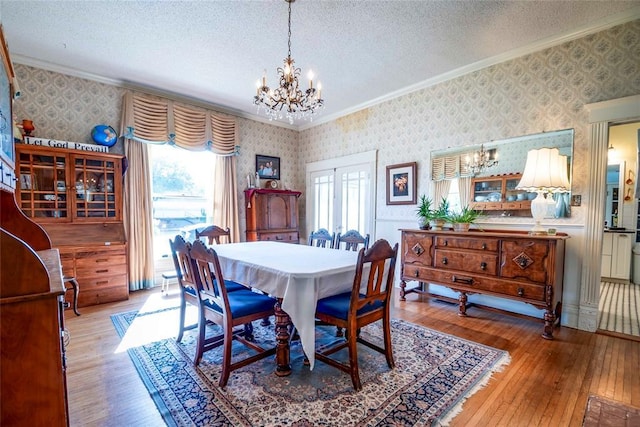 201 W 8th St, Chandler, OK 74834 - dining space featuring a chandelier, wallpapered walls, ornamental molding, hardwood / wood-style flooring, and a textured ceiling