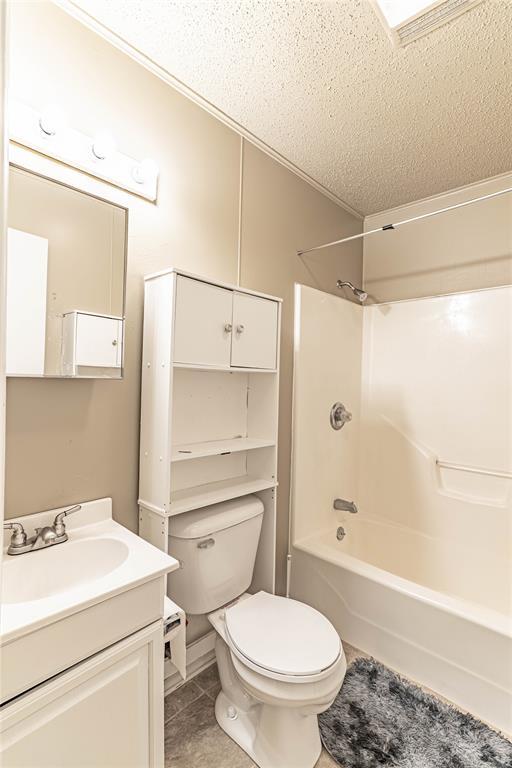 1343 E Moses St, Cushing, OK 74023 - full bathroom with toilet, a textured ceiling, vanity,  shower combination, and tile patterned flooring