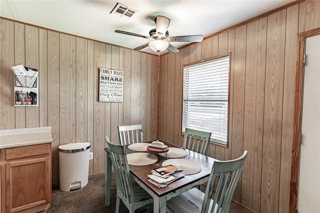 1343 E Moses St, Cushing, OK 74023 - dining area with ceiling fan, dark colored carpet, and wooden walls