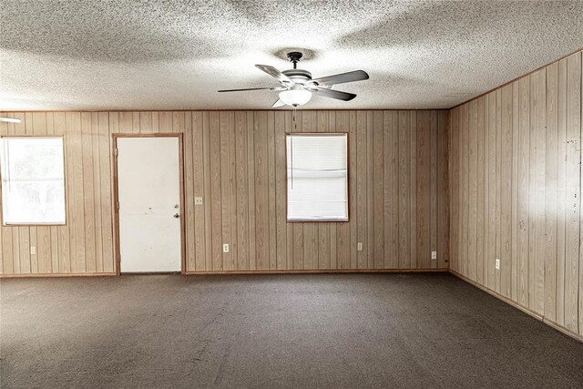 1343 E Moses St, Cushing, OK 74023 - carpeted spare room featuring ceiling fan, healthy amount of natural light, wooden walls, and a textured ceiling