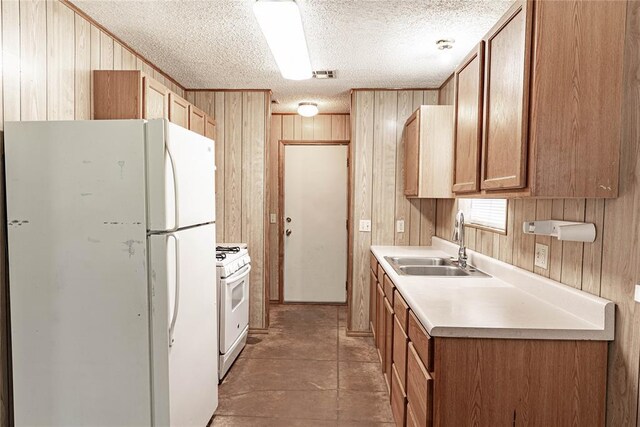 1343 E Moses St, Cushing, OK 74023 - kitchen featuring white appliances, a sink, wood walls, a textured ceiling, and light countertops