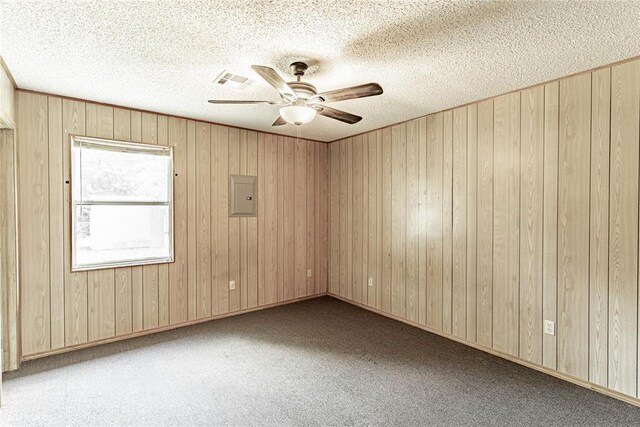 1343 E Moses St, Cushing, OK 74023 - carpeted empty room with electric panel, ceiling fan, a textured ceiling, and wood walls