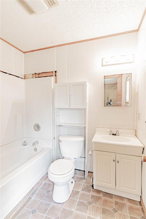 1343 E Moses St, Cushing, OK 74023 - full bath featuring a textured ceiling, toilet, vanity, ornamental molding, and shower / washtub combination