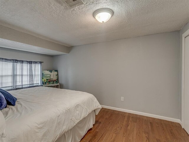 2417 SW 47th St, Oklahoma City, OK 73129 - bedroom with wood finished floors, baseboards, and a textured ceiling