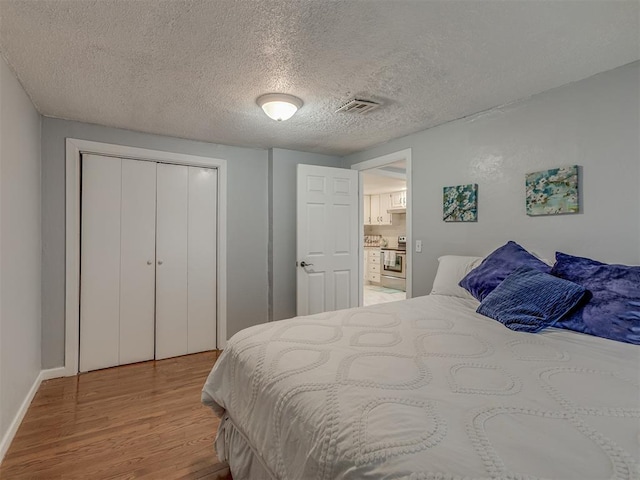 2417 SW 47th St, Oklahoma City, OK 73129 - bedroom with wood finished floors, a textured ceiling, a closet, and baseboards