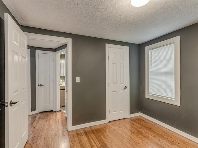 2417 SW 47th St, Oklahoma City, OK 73129 - unfurnished bedroom with light wood finished floors, baseboards, and a textured ceiling