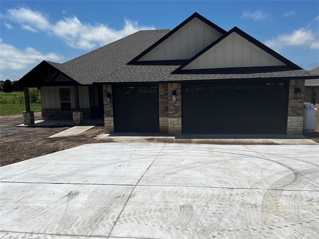 614 Canyon Dr Unit 4054964463, Ardmore, OK 73401 - view of front of property featuring a shingled roof, a garage, concrete driveway, board and batten siding, and stone siding