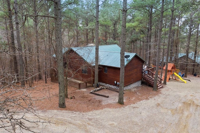 1073 Southern Hills Cir, Broken Bow, OK 74728 - view of home's exterior with faux log siding, a playground, a metal roof, and a view of trees