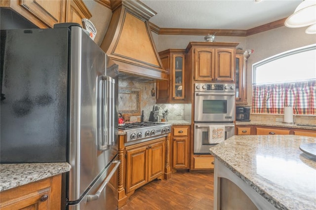 108 Raye Pl, Tuttle, OK 73089 - kitchen featuring stainless steel appliances, brown cabinets, ornamental molding, dark wood-type flooring, and decorative backsplash
