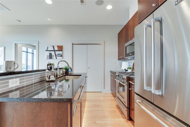 301 NE 4th St Unit 10, Oklahoma City, OK 73104 - kitchen with stainless steel appliances, a sink, light wood-style floors, dark stone countertops, and recessed lighting
