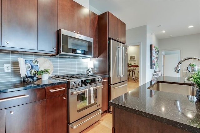 301 NE 4th St Unit 10, Oklahoma City, OK 73104 - kitchen with appliances with stainless steel finishes, a sink, dark stone counters, tasteful backsplash, and recessed lighting