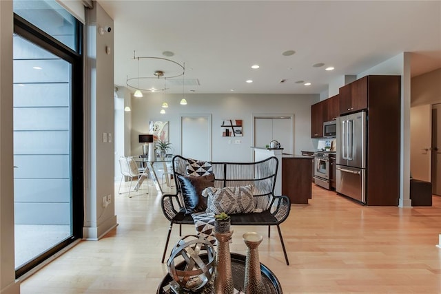 301 NE 4th St Unit 10, Oklahoma City, OK 73104 - kitchen with high end appliances, light wood-style floors, dark brown cabinetry, a center island, and recessed lighting