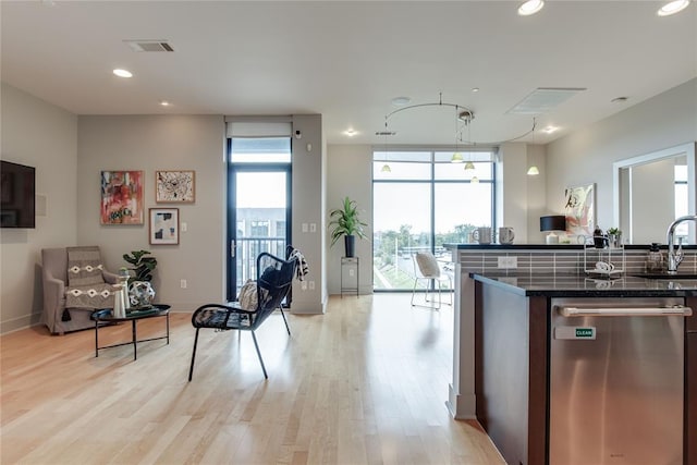 301 NE 4th St Unit 10, Oklahoma City, OK 73104 - kitchen with stainless steel dishwasher, light wood-style floors, dark stone countertops, recessed lighting, and a sink