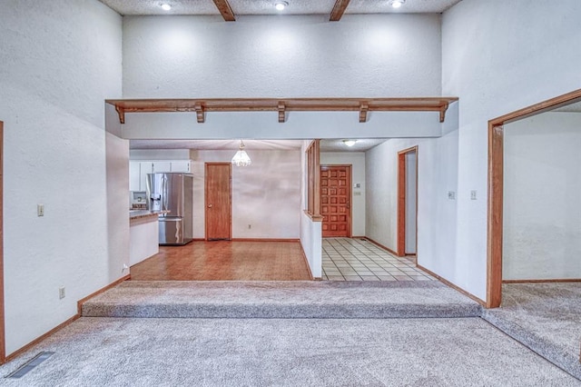 2804 Meadow Ave, Norman, OK 73072 - unfurnished living room with light carpet, a textured wall, beamed ceiling, baseboards, and recessed lighting