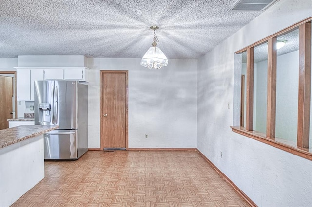 2804 Meadow Ave, Norman, OK 73072 - kitchen featuring stainless steel fridge, a chandelier, a textured ceiling, white cabinetry, and light countertops