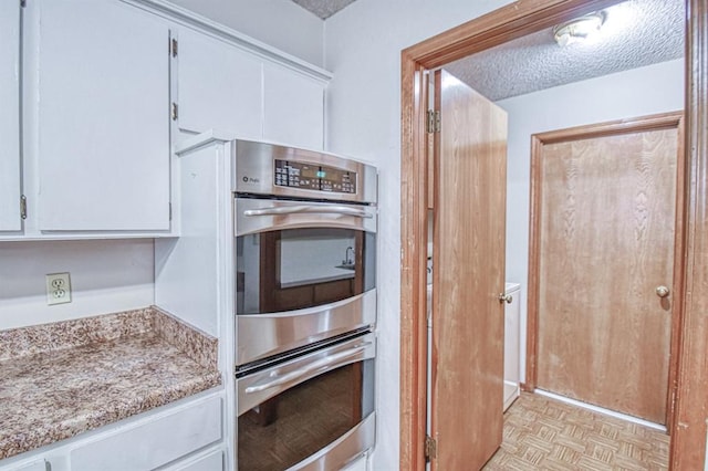 2804 Meadow Ave, Norman, OK 73072 - kitchen with white cabinets, stainless steel double oven, a textured ceiling, and light stone counters