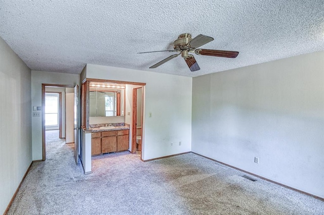 2804 Meadow Ave, Norman, OK 73072 - unfurnished bedroom with light colored carpet, a sink, a textured ceiling, baseboards, and a ceiling fan