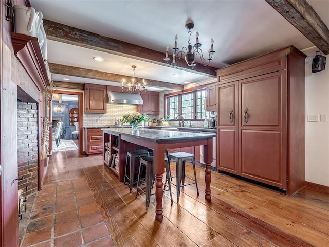 4005 NE 122nd St, Edmond, OK 73013 - kitchen featuring a chandelier, ventilation hood, beam ceiling, a kitchen breakfast bar, and a kitchen island