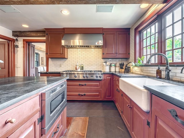 4005 NE 122nd St, Edmond, OK 73013 - kitchen with wall chimney range hood, stainless steel appliances, decorative backsplash, dark countertops, and recessed lighting
