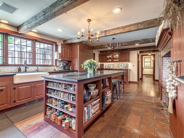 4005 NE 122nd St, Edmond, OK 73013 - kitchen with open shelves, a chandelier, beam ceiling, a center island, and decorative backsplash
