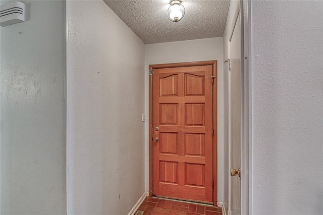 342 W Birch Dr, Mustang, OK 73064 - doorway with brick patterned flooring and a textured ceiling