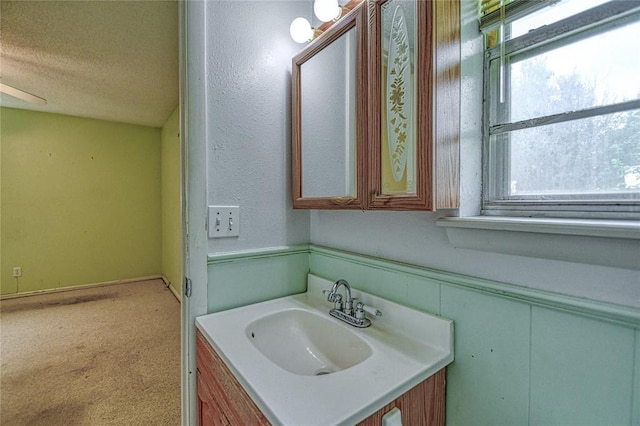 342 W Birch Dr, Mustang, OK 73064 - bathroom featuring vanity, a textured ceiling, and a wainscoted wall