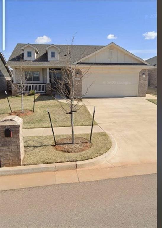 6821 NW 155th St, Edmond, OK 73013 - view of front of home with driveway, a garage, board and batten siding, roof with shingles, and a front yard