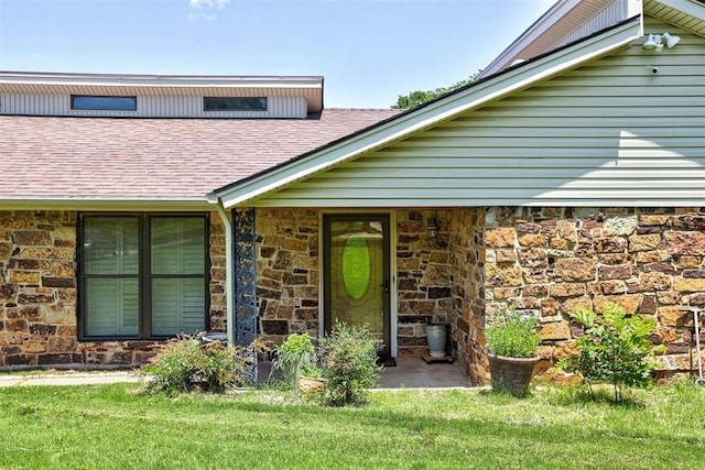 11129 E Thayer St, Midwest City, OK 73130 - doorway to property with stone siding, roof with shingles, and a lawn