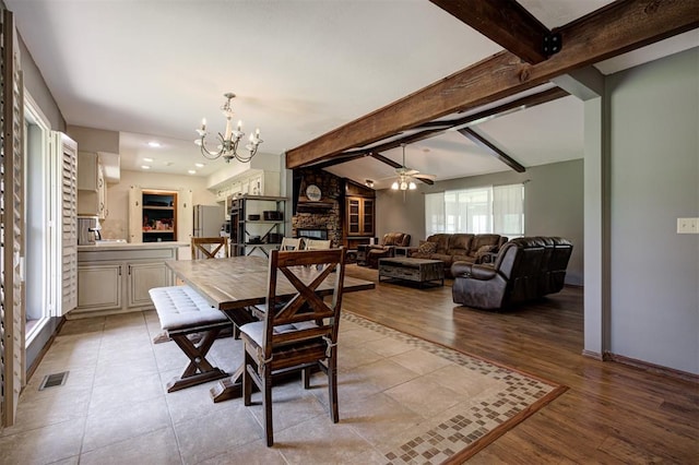 11129 E Thayer St, Midwest City, OK 73130 - dining space featuring a stone fireplace, a ceiling fan, beamed ceiling, a chandelier, and light wood-style floors