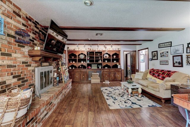 801 Bonnie Ave, Purcell, OK 73080 - living area featuring a textured ceiling, wood-type flooring, a brick fireplace, and beam ceiling