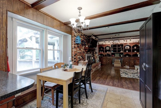 801 Bonnie Ave, Purcell, OK 73080 - dining space featuring a chandelier, a brick fireplace, ornamental molding, beamed ceiling, and a textured ceiling